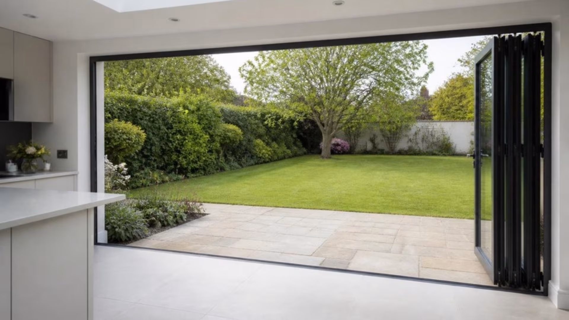 Aluminium bifold doors folded open from a kitchen extension to the garden