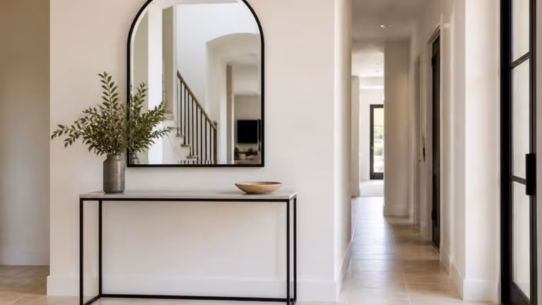 Arched black-framed mirror above a hallway console table