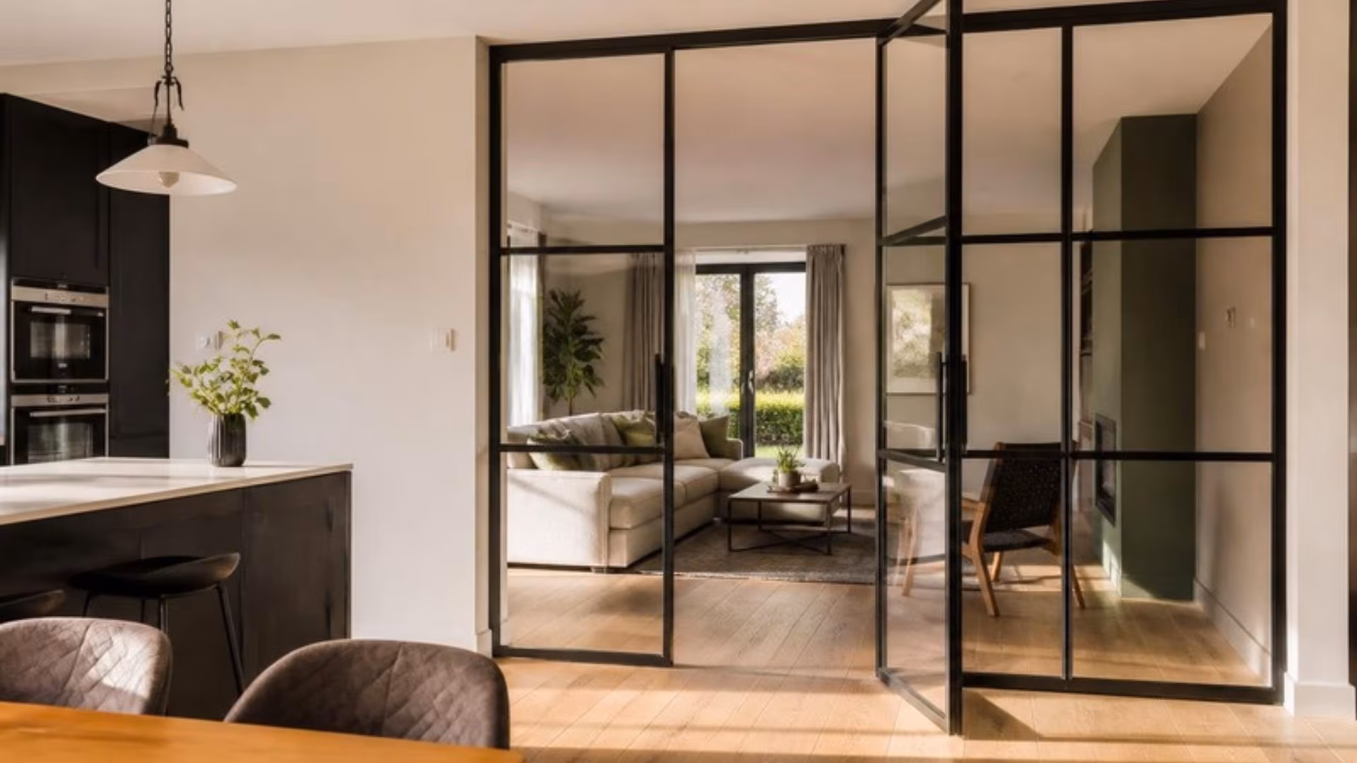 Black-framed glass partition between a kitchen and living room