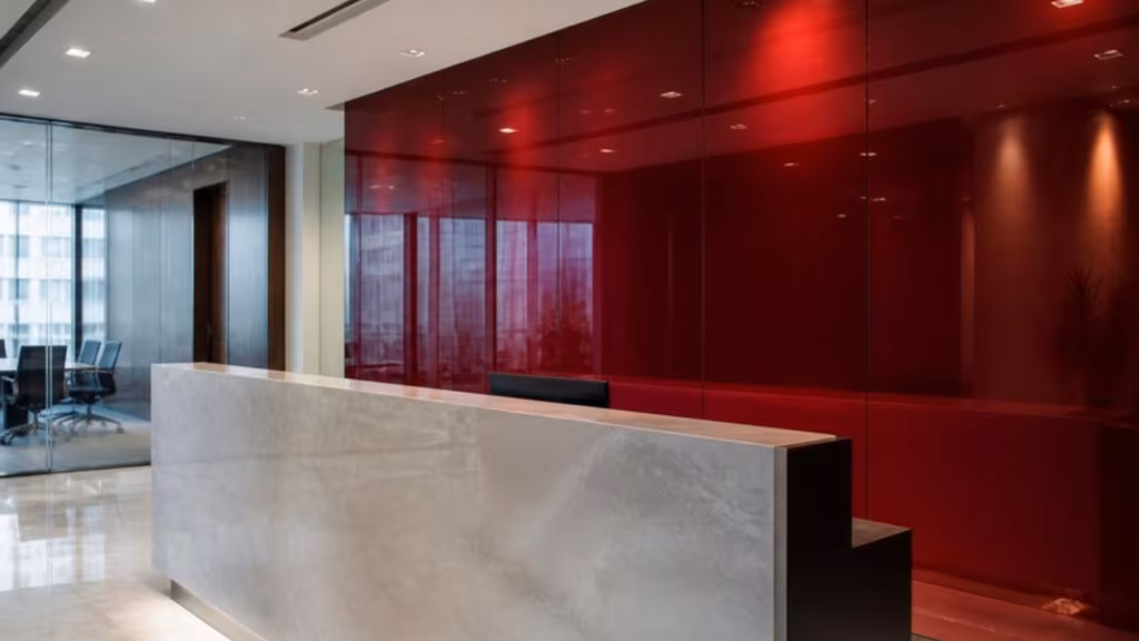 Deep red colour-backed glass wall panel behind a reception desk