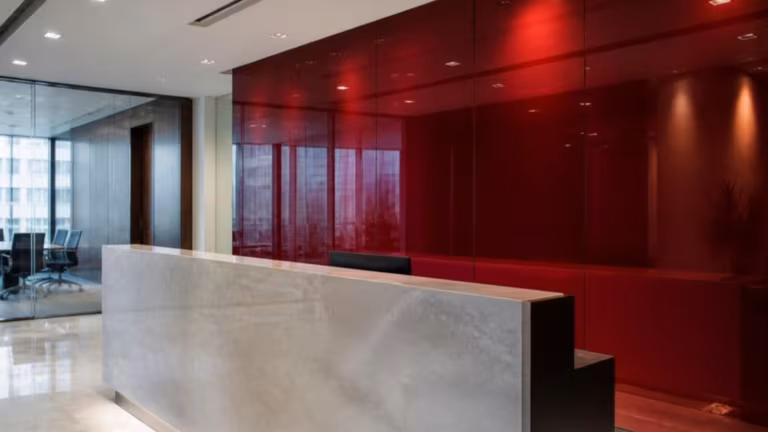 Deep red colour-backed glass wall panel behind a reception desk