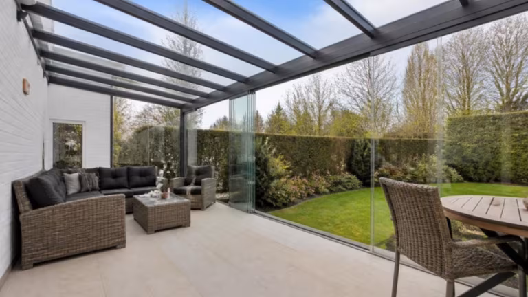 Glass-roofed veranda with frameless sliding glass walls
