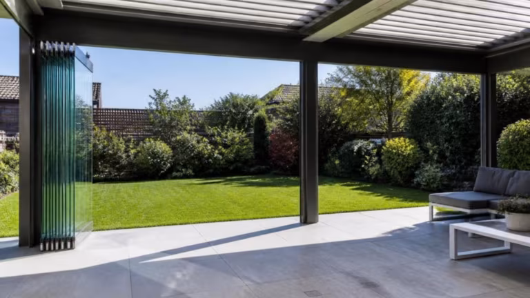 Frameless glass sliding walls stacked to one side under a veranda