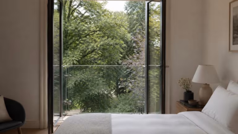 French doors opening onto a glass Juliet balcony from a bedroom
