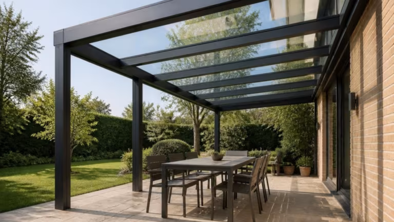Aluminium pergola with a clear glass roof over an outdoor dining table