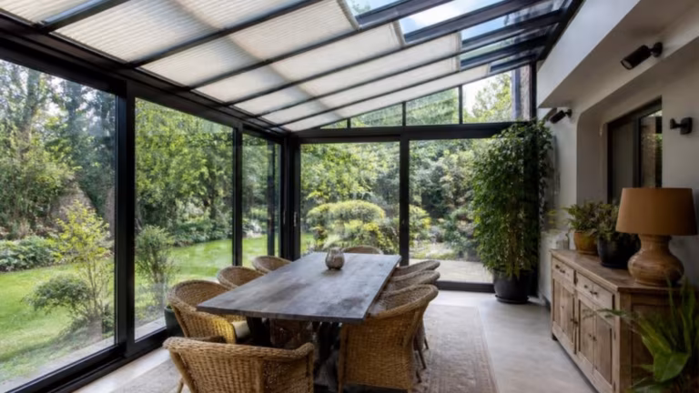 Glass room used as a dining room with roof blinds and plants