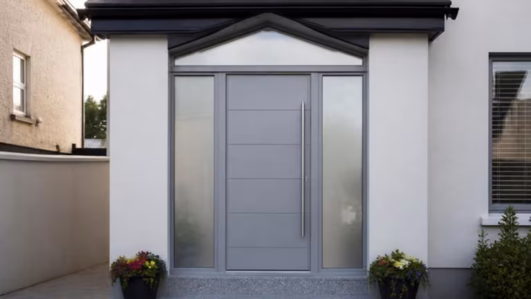 Grey aluminium front door with frosted sidelights on a rendered house