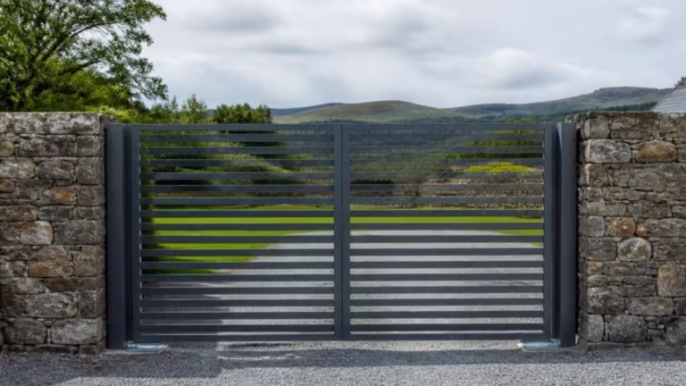 Grey horizontal slatted aluminium swing gates between stone walls