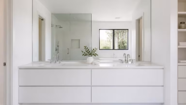 Large frameless mirror in a bright white bathroom