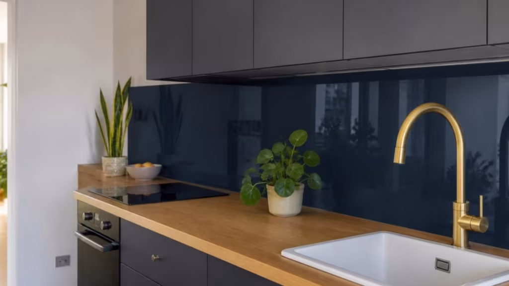 Navy glass splashback with socket cut-outs above an oak worktop