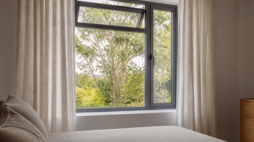 Bedroom with a grey aluminium casement window and an open top-hung vent