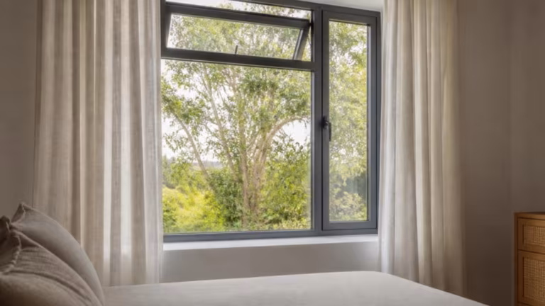 Bedroom with a grey aluminium casement window and an open top-hung vent