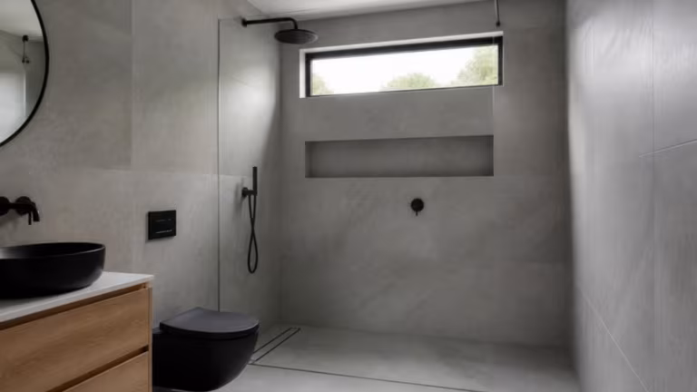 Walk-in shower with a frameless glass panel and matt black fittings