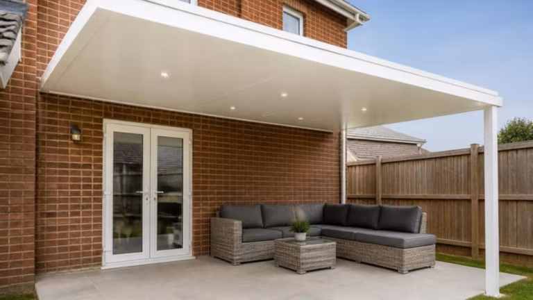 Wall-mounted white aluminium pergola with a solid roof and downlights