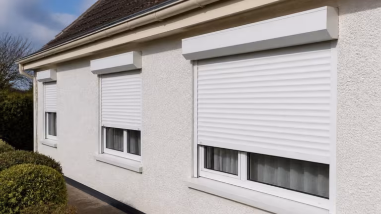 White electric roller shutters half closed on a bungalow